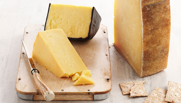 A picture of different styles of cheddar, served with crackers on a cheese platter. 