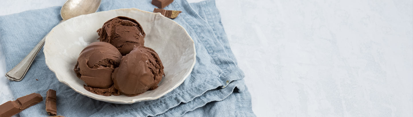 A picture of a bowl of chocolate ice cream, served on a table. 